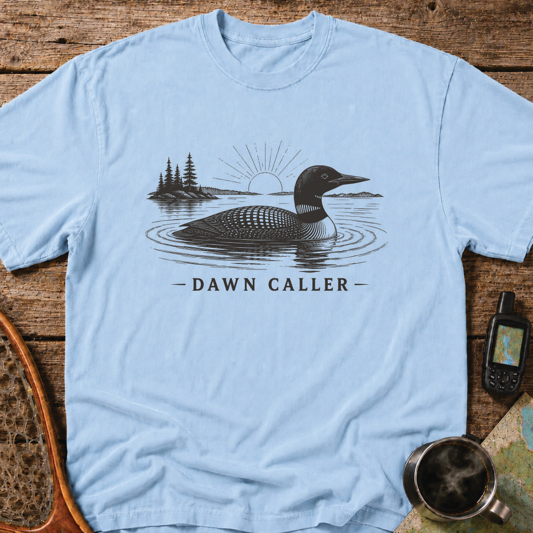 Dawn Caller loon t-shirt featuring a detailed loon floating on a northern lake at sunrise with wilderness shoreline artwork.