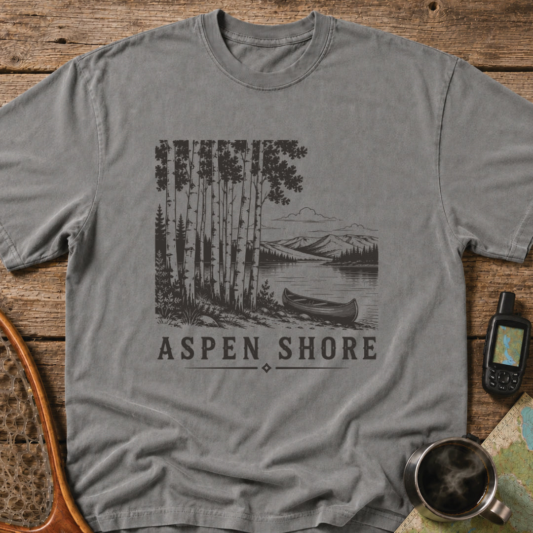 Vintage canoe resting beside a wilderness lake surrounded by aspen trees and mountain scenery.