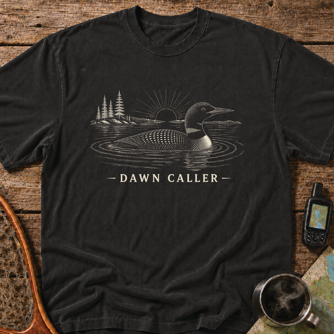 Dawn Caller loon t-shirt featuring a detailed loon floating on a northern lake at sunrise with wilderness shoreline artwork.