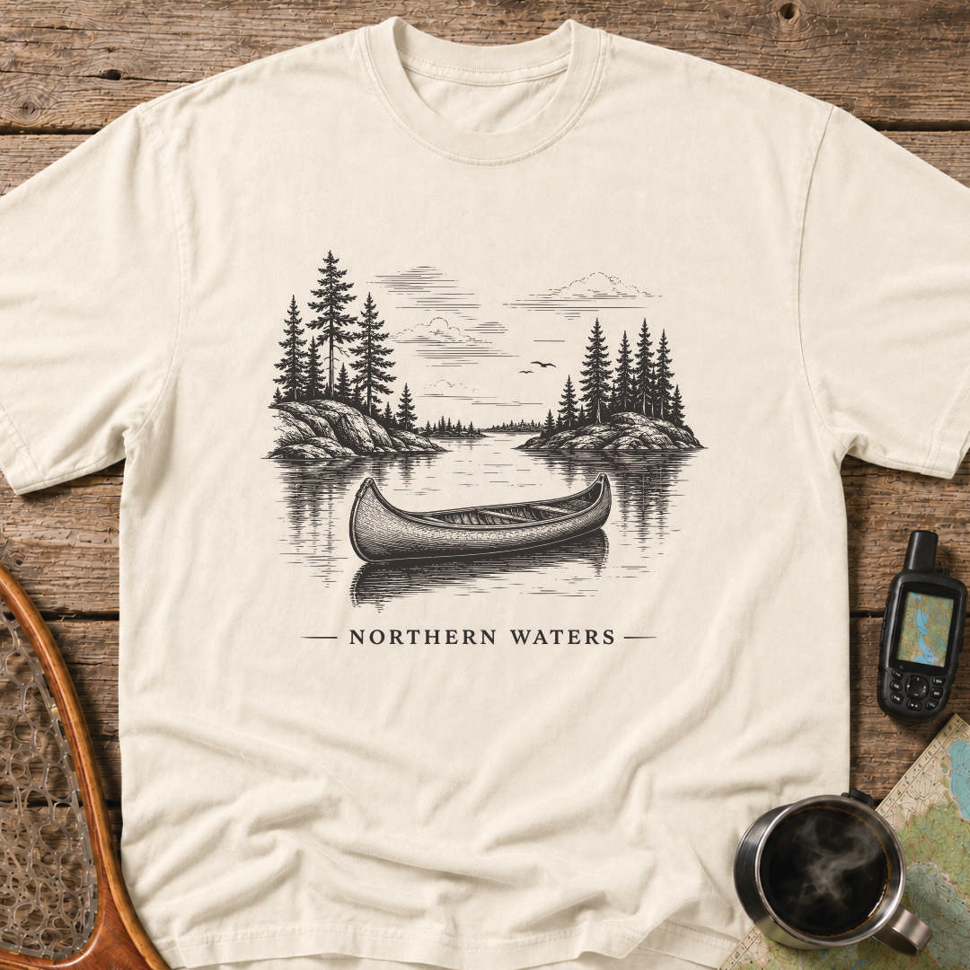 Northern Waters t-shirt featuring a canoe floating on a calm wilderness lake surrounded by pine-covered islands.