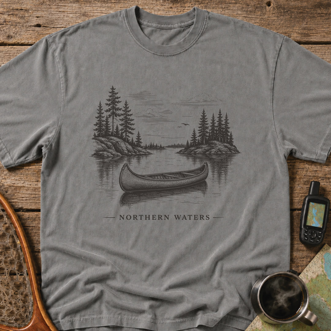 Northern Waters t-shirt featuring a canoe floating on a calm wilderness lake surrounded by pine-covered islands.